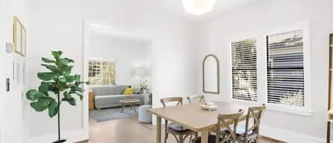 A dining area with a wooden table and chairs, a potted plant, and a hanging light fixture.