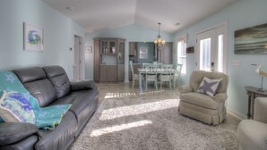 A spacious living room with a leather sofa, a fluffy rug, and a dining area with a table and chairs.