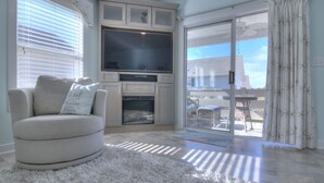 A living room with a grey sofa, a flat-screen TV, and a fireplace.