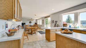 A modern kitchen with wooden cabinets, a large island, and a dining area with chairs. - Hoodsport Vacation Rental w/ Deck & Canal Views! (Hoodsport)