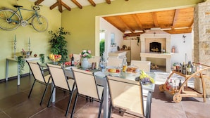 A dining area with a table set for four, a bicycle hanging on the wall, and a stone fireplace. - Villa mit Pool und Klimaanlage (Žminj)