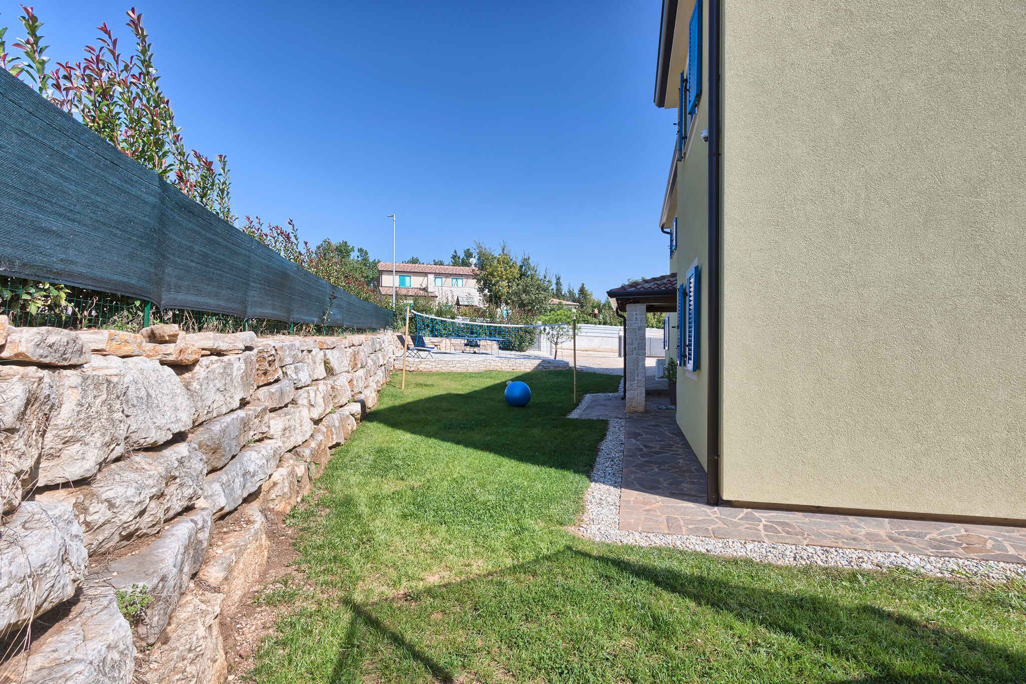 A stone wall, a grassy area, and a building with a blue door.