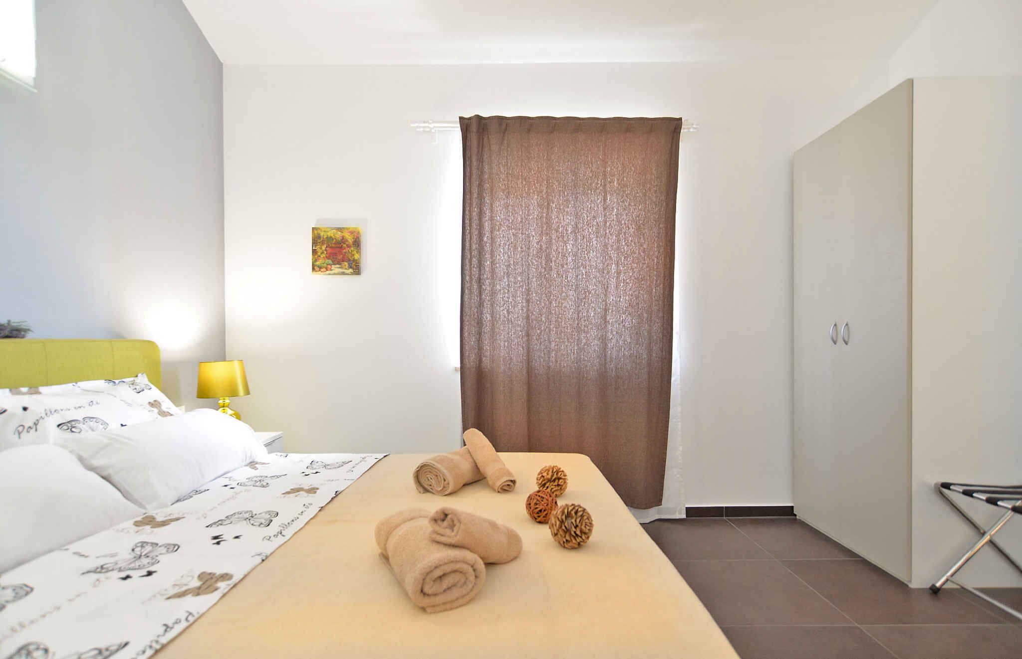 Une chambre d’hôtel avec un lit, une table de chevet avec une lampe, une fenêtre avec des rideaux et un tableau au mur.