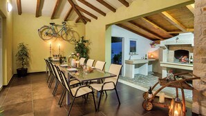 A dining area with a table set for six, a bicycle hanging from the ceiling, and a stone fireplace in the background. - Villa mit Pool und Klimaanlage (Žminj)