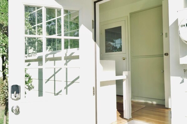 A white door with a window, a small step leading to a wooden floor, and a white wall with a door to the right. - The Miller Farmhouse (Harrisburg)