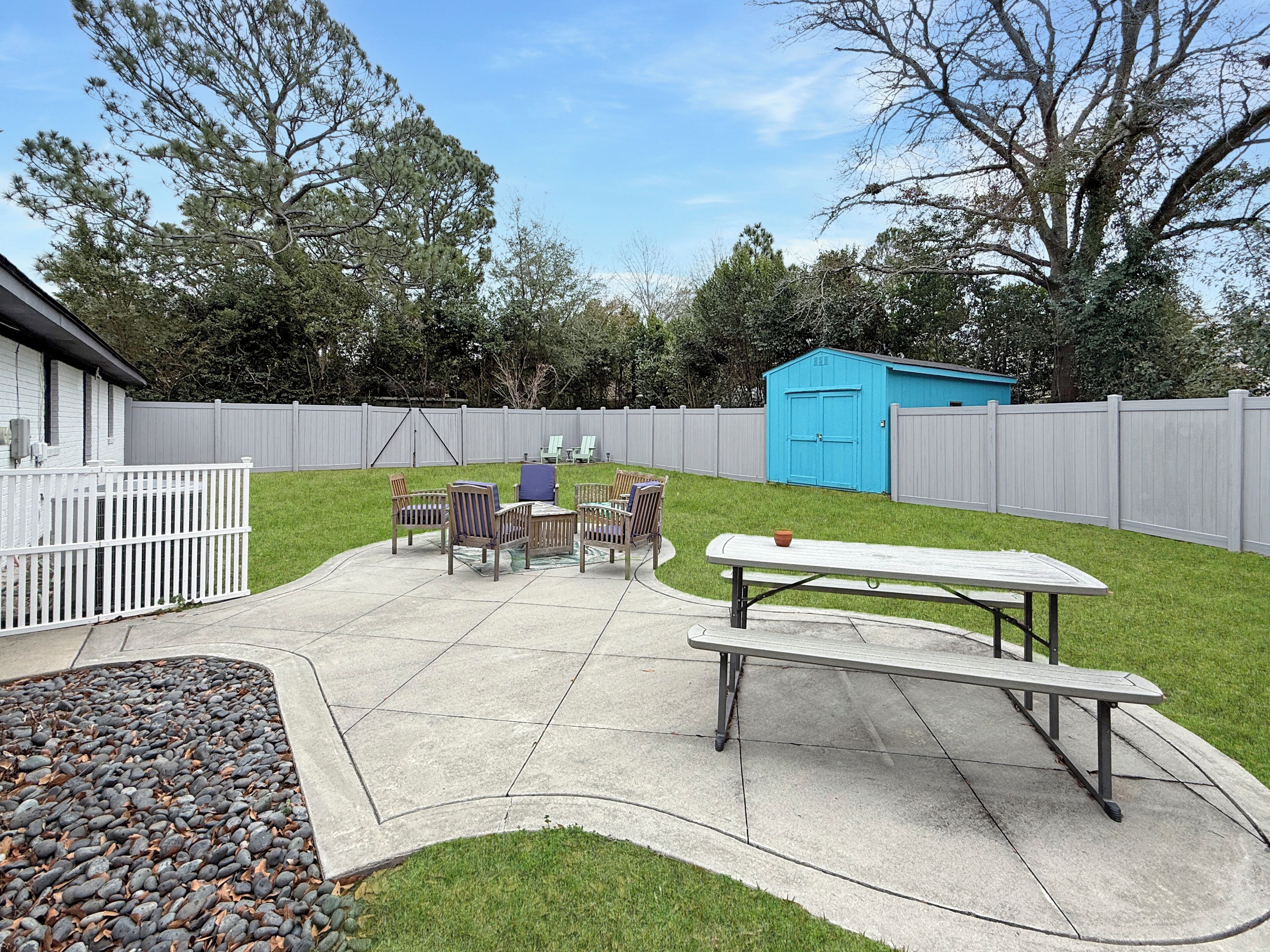 A backyard with a picnic table, chairs, and a shed.