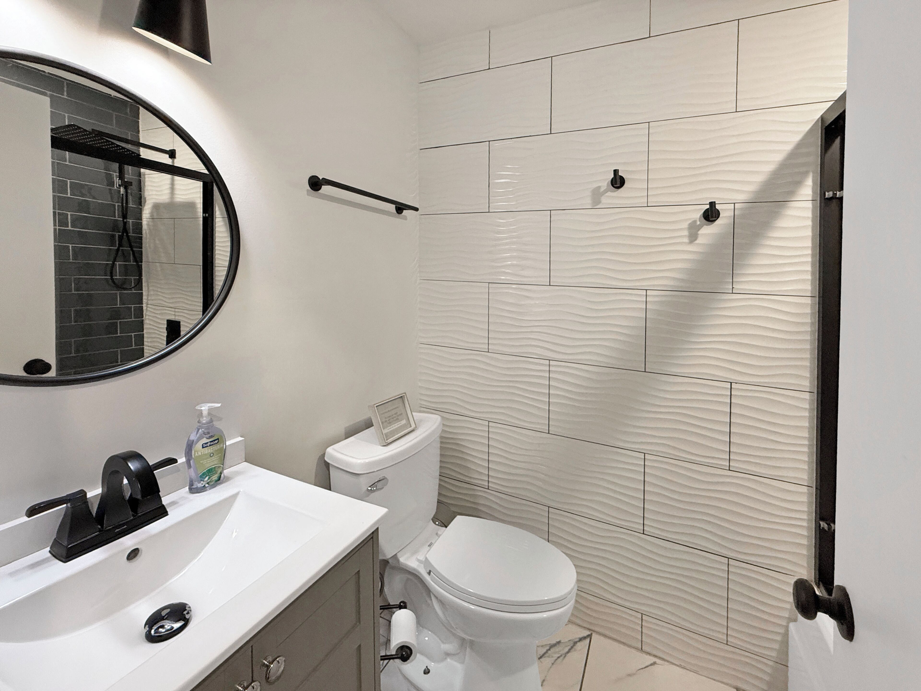 A modern bathroom with a white sink, a toilet, and a shower area.