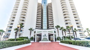 Un hôtel moderne doté d’une tour centrale en verre, de nombreux balcons et d’une entrée en briques rouges.
