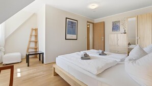 Ein Schlafzimmer mit einem Bett, einer Holzleiter, einem gerahmten Bild und einem Kleiderschrank.