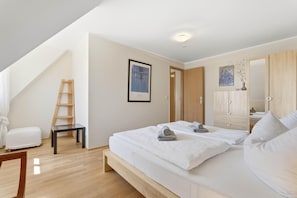 Ein Schlafzimmer mit einem Bett, einer Holzleiter, einem gerahmten Bild und einem Kleiderschrank.