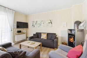 A living room with a sofa, a coffee table, a fireplace, a TV, and artwork on the wall.