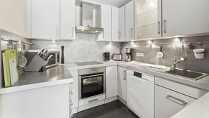 Eine moderne Küche mit weißen Schränken, Edelstahlgeräten und einem eingebauten Backofen.