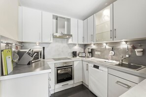 A modern kitchen with white cabinets, stainless steel appliances, and a built-in oven.