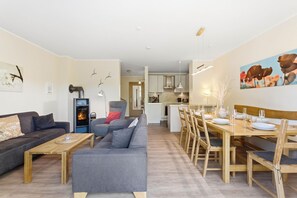Ein modernes Wohnzimmer mit Kamin, Sofa und Essbereich mit Holzmöbeln.