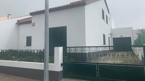 Ein modernes Gebäude mit weißer Fassade, grünen Fensterläden und einem roten Ziegeldach.