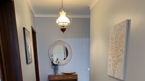 Ein Flur mit einem Holztischchen, einem Spiegel und einem gerahmten Bild an der Wand.