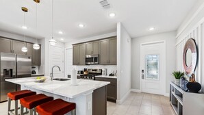A modern kitchen with a central island, stainless steel appliances, and a large window.