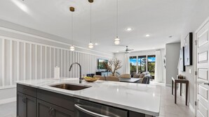 A modern kitchen with a large island, stainless steel appliances, and pendant lighting.