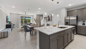 A modern kitchen with a large island, stainless steel appliances, and a dining area with a view.