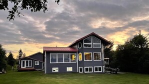 Ein zweistöckiges Haus mit rotem Dach, großen Fenstern und einem gepflegten Rasen.