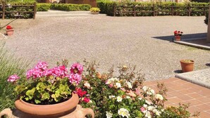 Eine traditionelle Villa im mediterranen Stil mit Steinverkleidung, einem Innenhof und einem großen Garten mit blühenden Pflanzen.