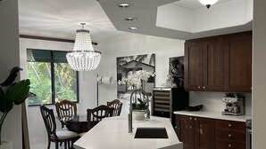 Een moderne keuken met een centraal eiland, houten kastjes en een kroonluchter.