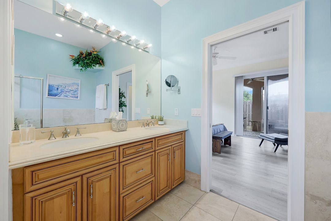 A bathroom with wooden cabinets, a large mirror, and a vanity with a lighted vanity mirror.