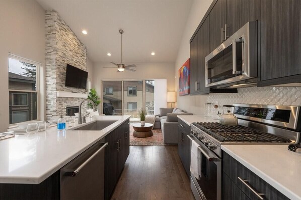 A modern kitchen with a stone accent wall, a large island, a built-in oven, and a microwave.