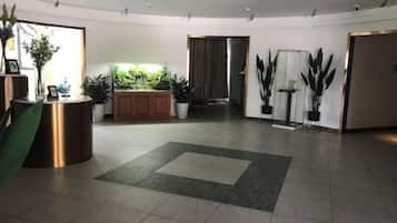 Un hall d’hôtel comprenant un comptoir d’accueil, un mur végétal et un sol carrelé.