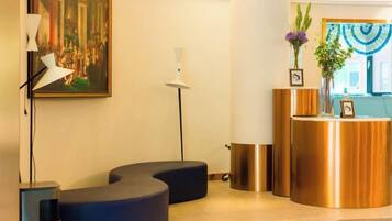 A reception area with a curved reception desk, a framed painting on the wall, and a floor lamp.