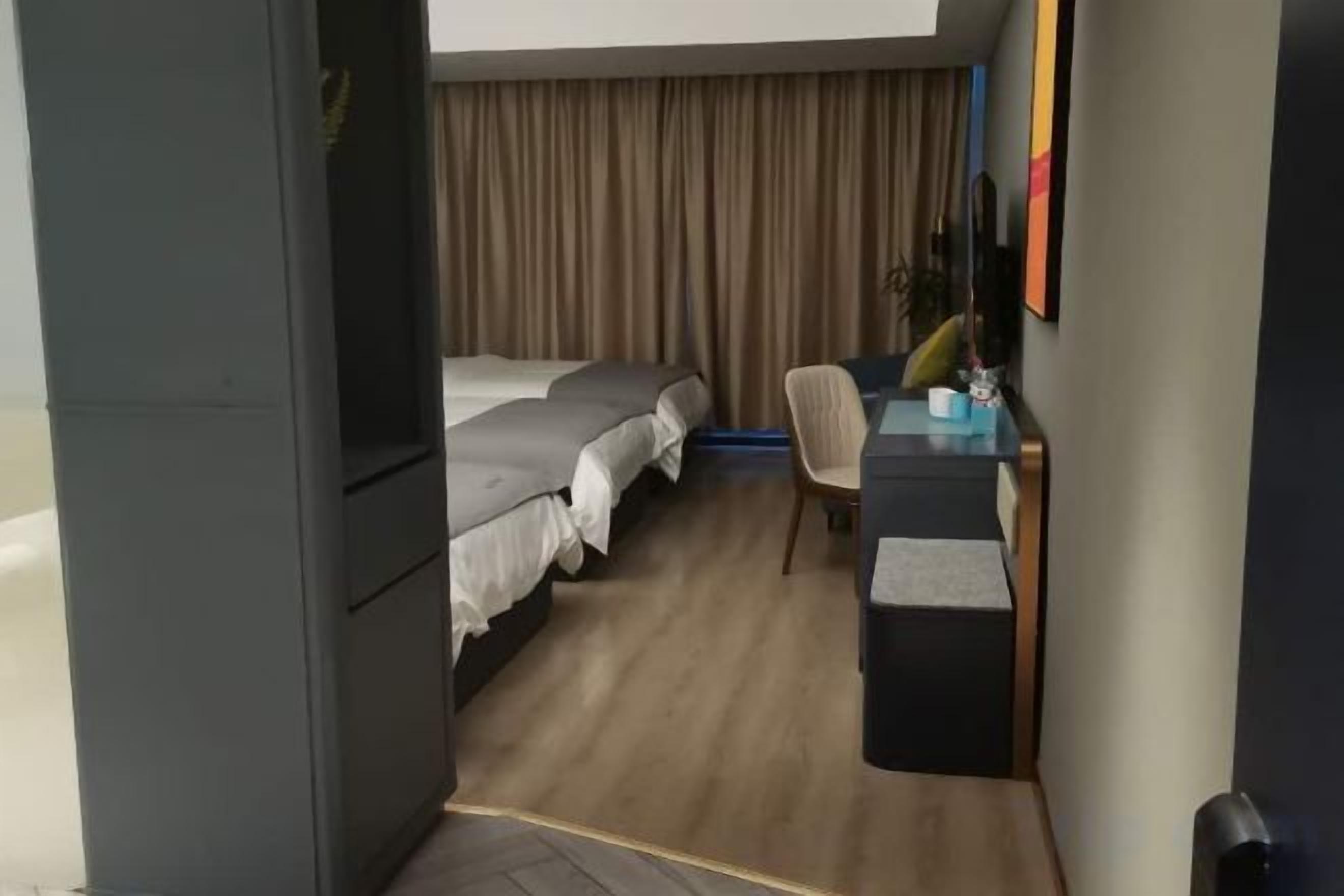 A hotel room with a bed, a desk, a chair, and a curtain.