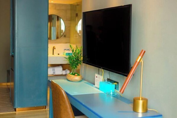 A modern bathroom with a large mirror, a sink, a television, and a desk with a plant and a lamp. - LANOU Hotel (Lanling Agricultural Park) (Lanling)