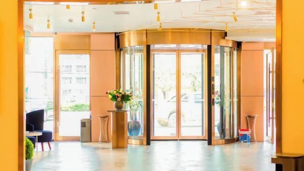 Un vestíbul d'hotel amb una porta giratòria, una recepció i una zona de seients.