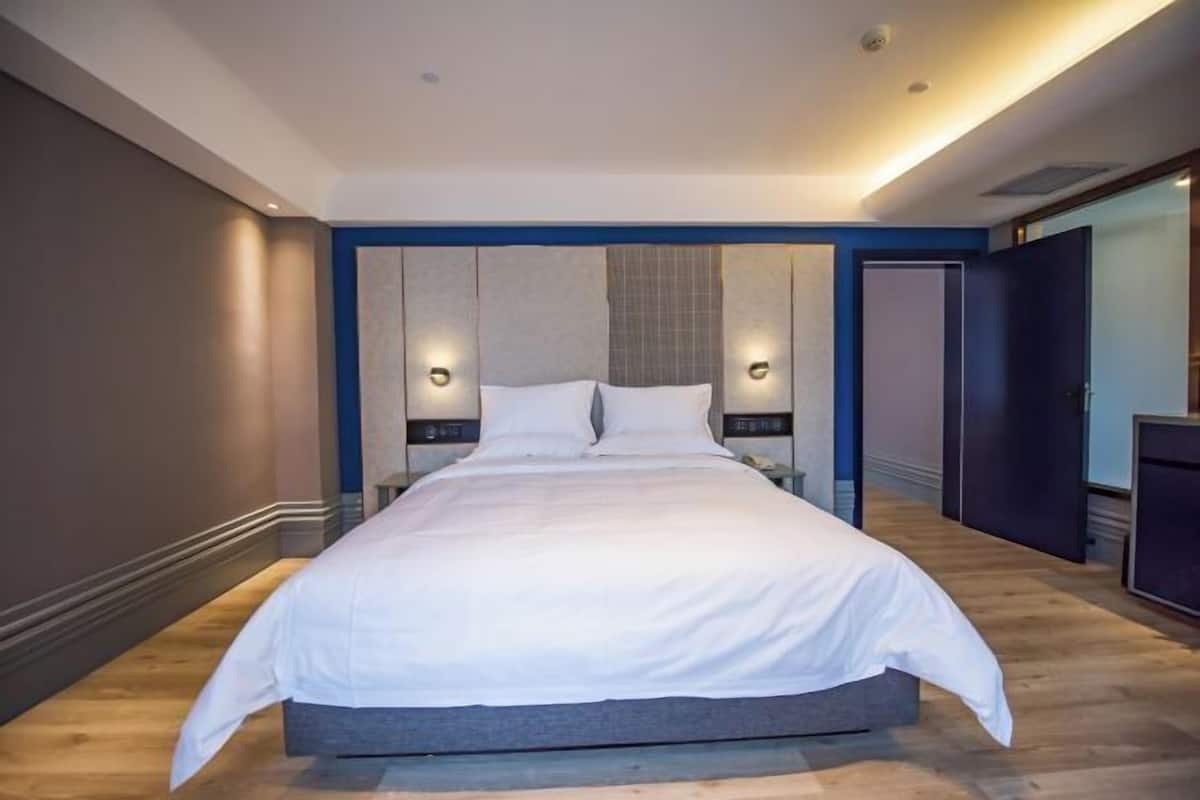 A modern bedroom with a large bed, two bedside tables, and wall-mounted lighting.