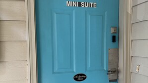 Eine türkisblaue Tür mit einem Schild, auf dem „MINI SUITE“ und ein „Nichtraucher“-Schild steht.