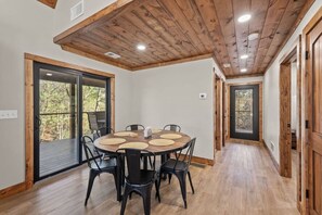A dining area with a round table, black chairs, and a wooden ceiling. - Anchor Point- Hot Tub, Firepit, Ping Pong (Rogers)