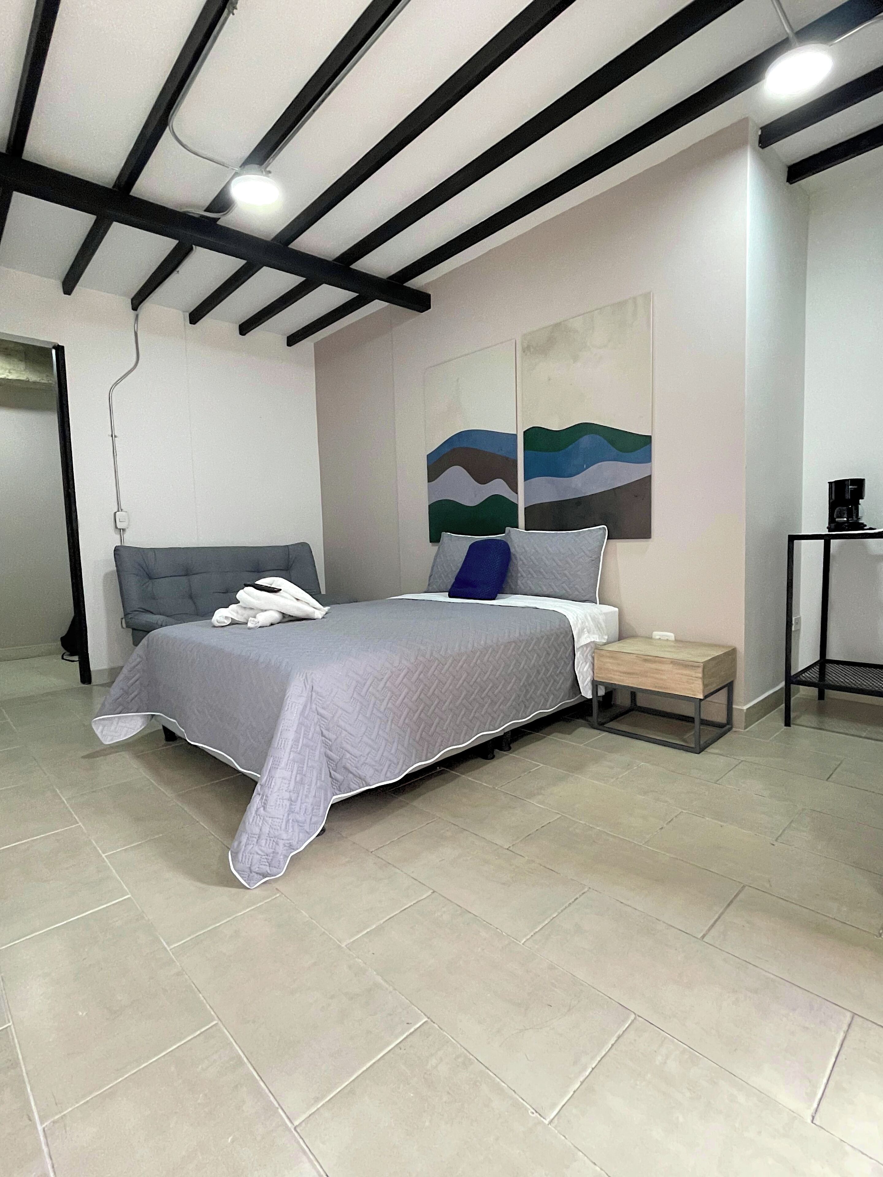 Een moderne slaapkamer met een bed, nachtkastje en kunst aan de muur.