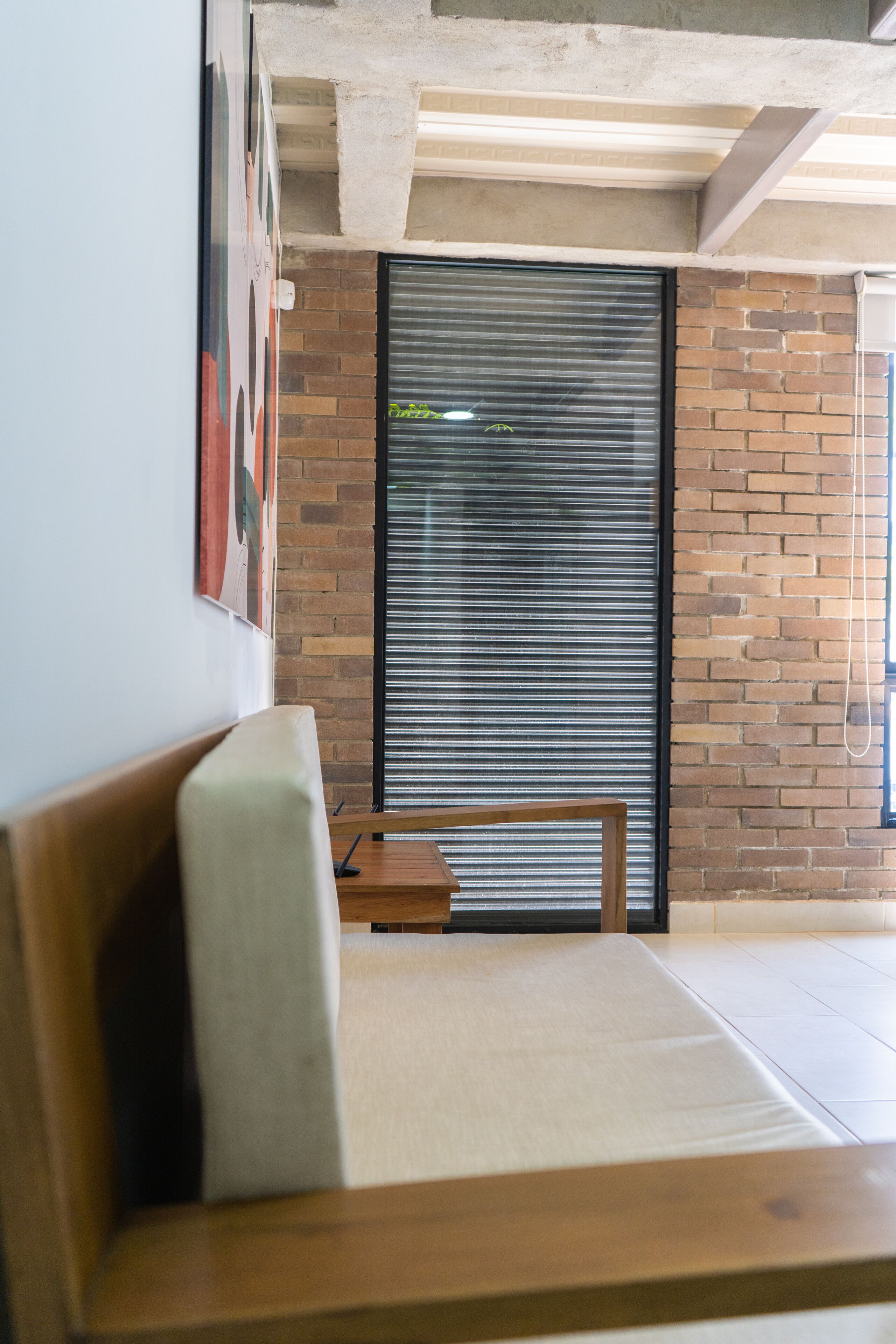 A modern interior with a wooden bench, a closed metal shutter, and a brick wall.