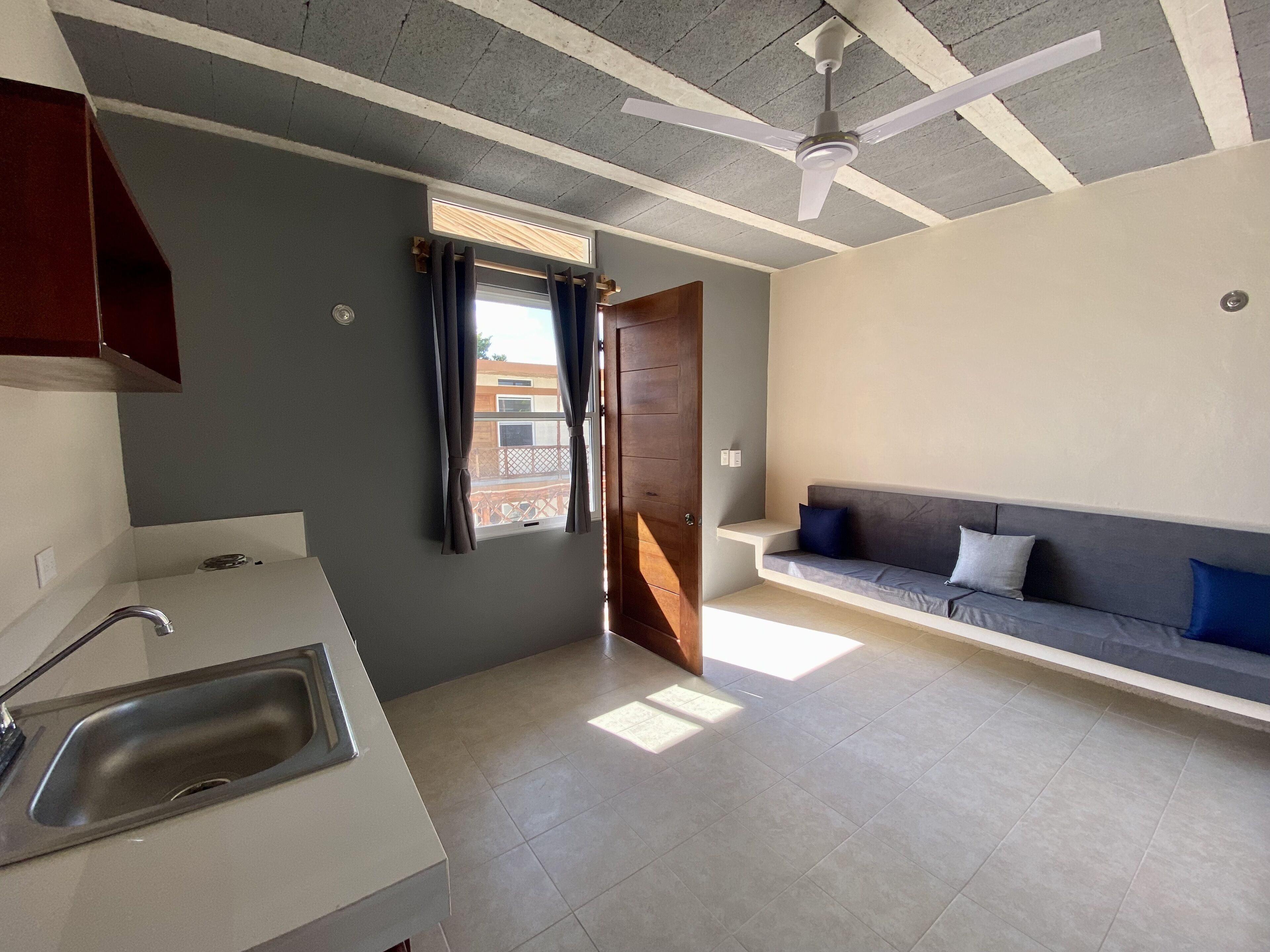 A modern kitchen with a sink and a window with curtains.