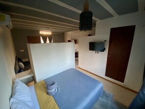 A bedroom with a bed, a TV mounted on the wall, and a door. - Casa Cielito Lindo Cozumel (Cozumel)