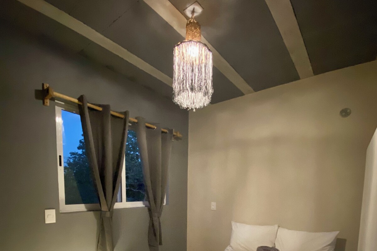 Un dormitorio con cama, cortinas, una araña y una ventana.