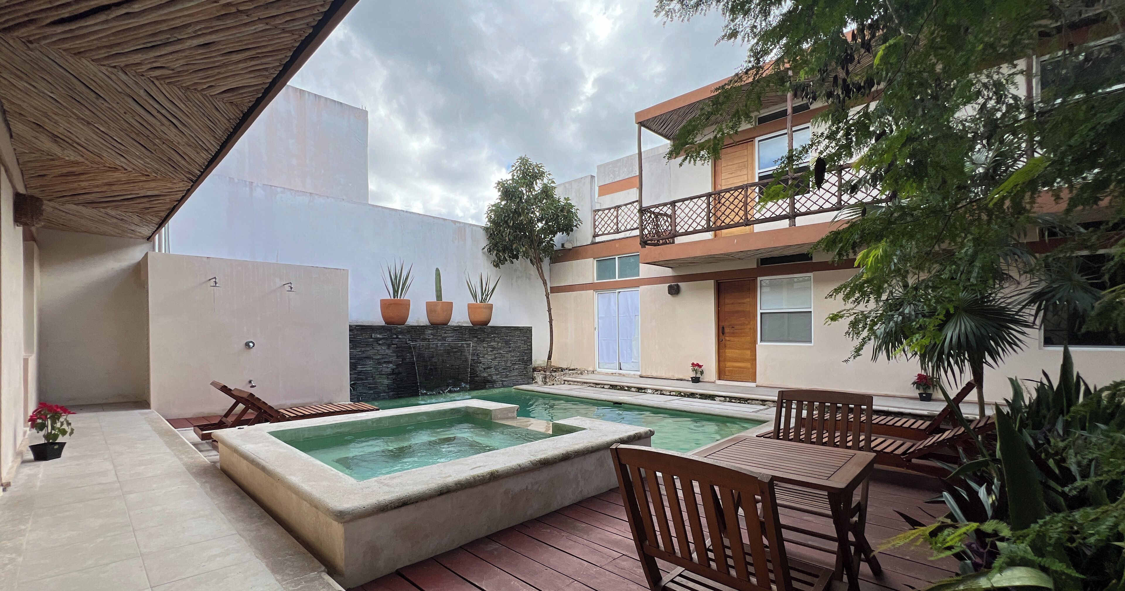 A courtyard with a swimming pool, wooden deck chairs, and potted plants.
