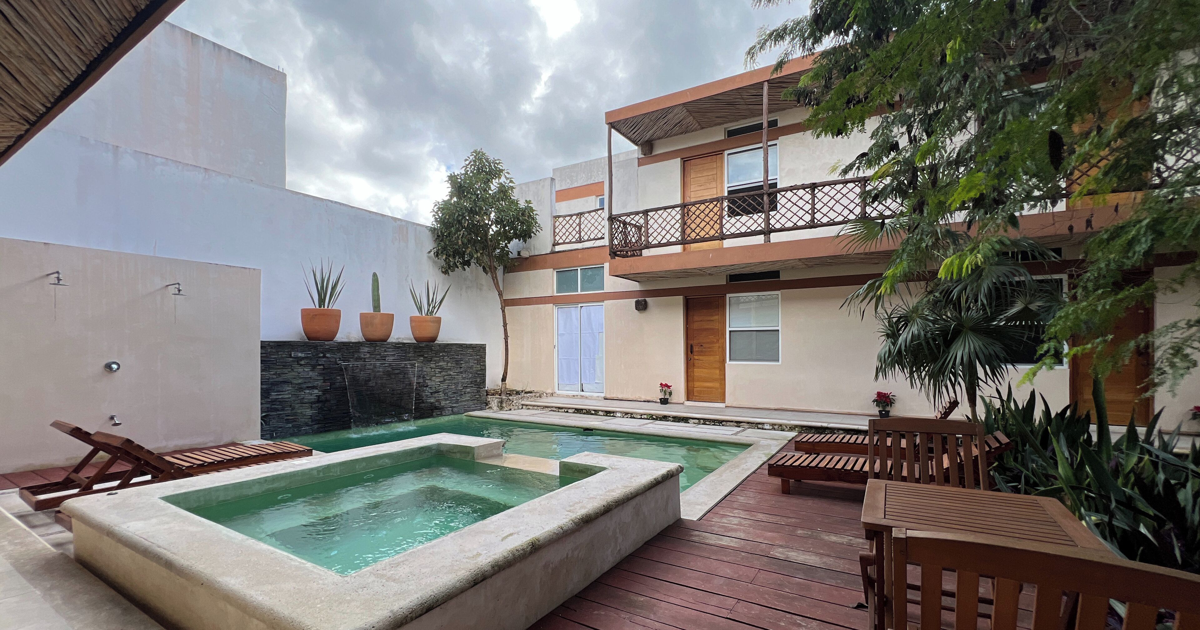 Un patio con piscina, terraza de madera y mobiliario exterior.