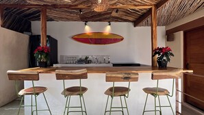 A rustic kitchen with a wooden island and bar stools. - Casa Cielito Lindo Cozumel (Cozumel)