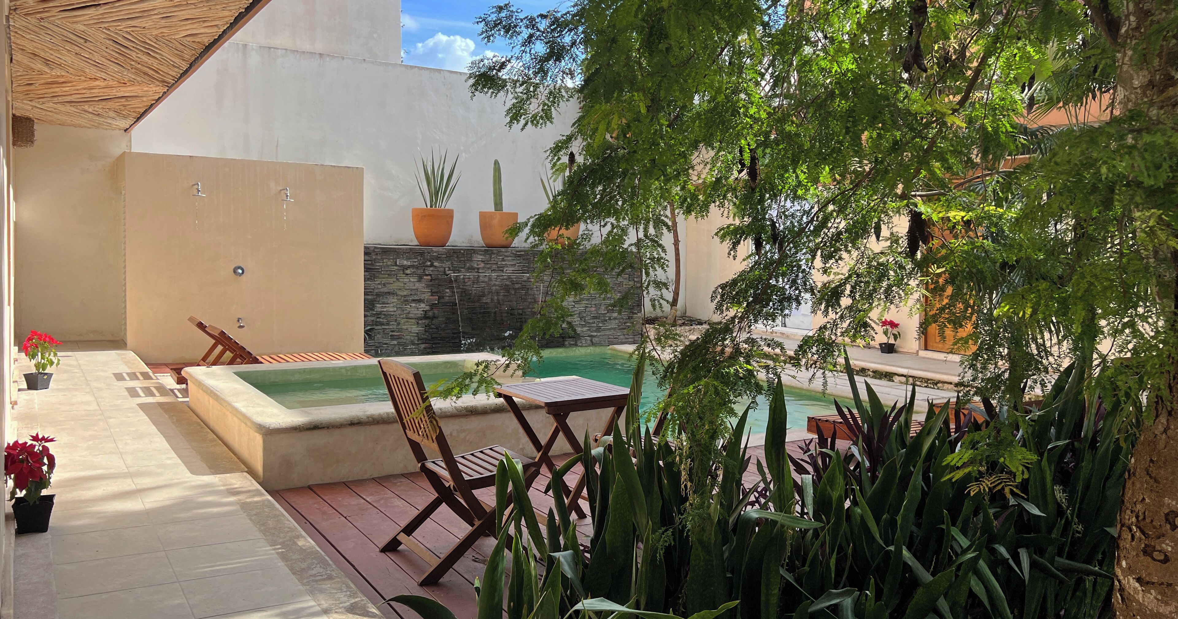 Un patio con un jacuzzi, mobiliario de madera y plantas en macetas.