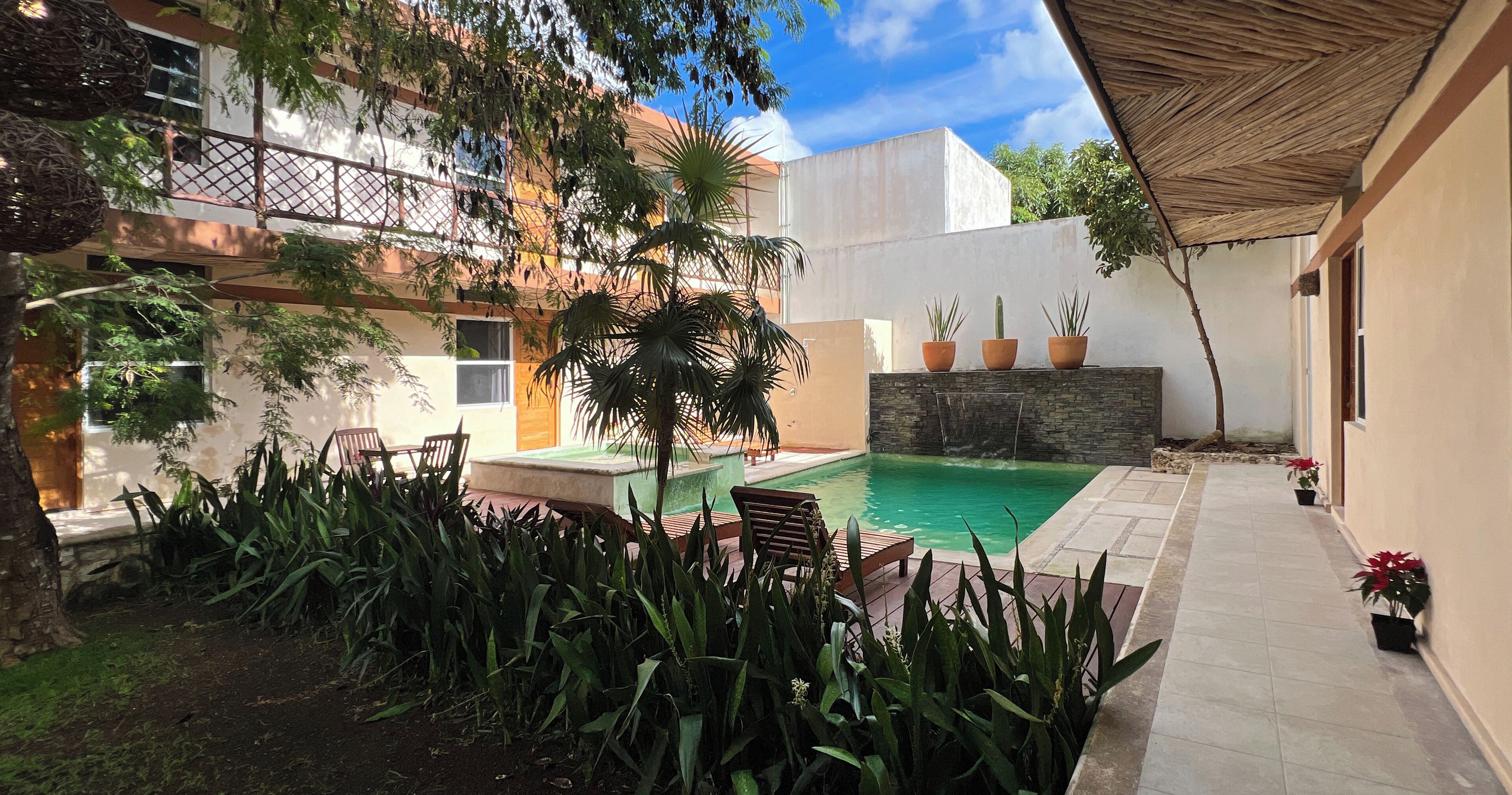 A courtyard with a swimming pool, potted plants, and a stone wall.