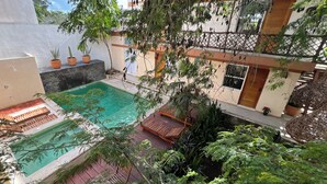 A rooftop pool area with a wooden deck, potted plants, and a view of the surrounding buildings. - Casa Cielito Lindo Cozumel (Cozumel)