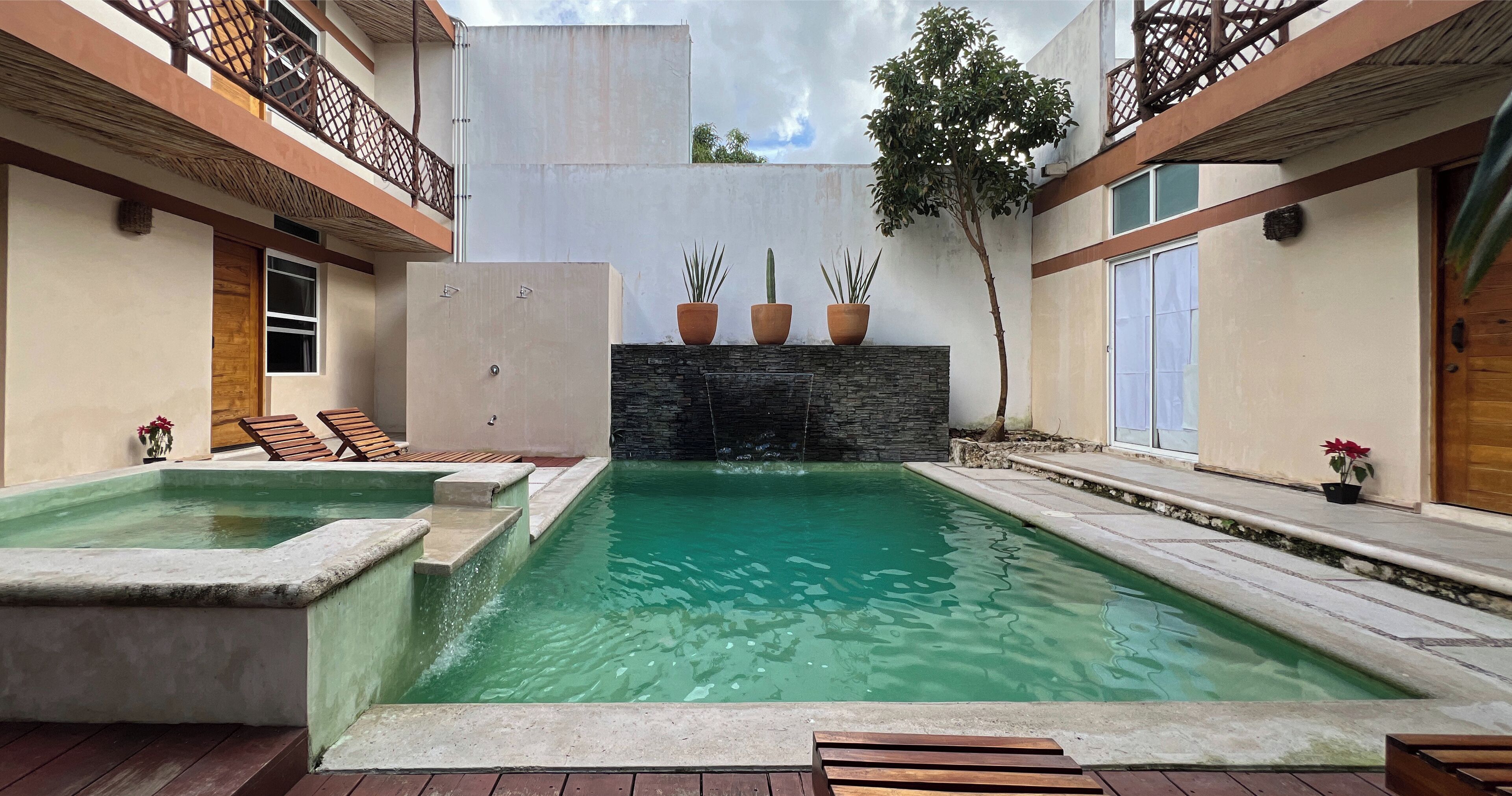 Una piscina con muro de piedra y plantas en macetas.