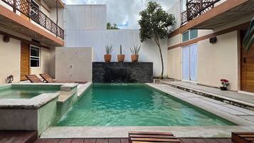 Una piscina con muro de piedra y plantas en macetas.