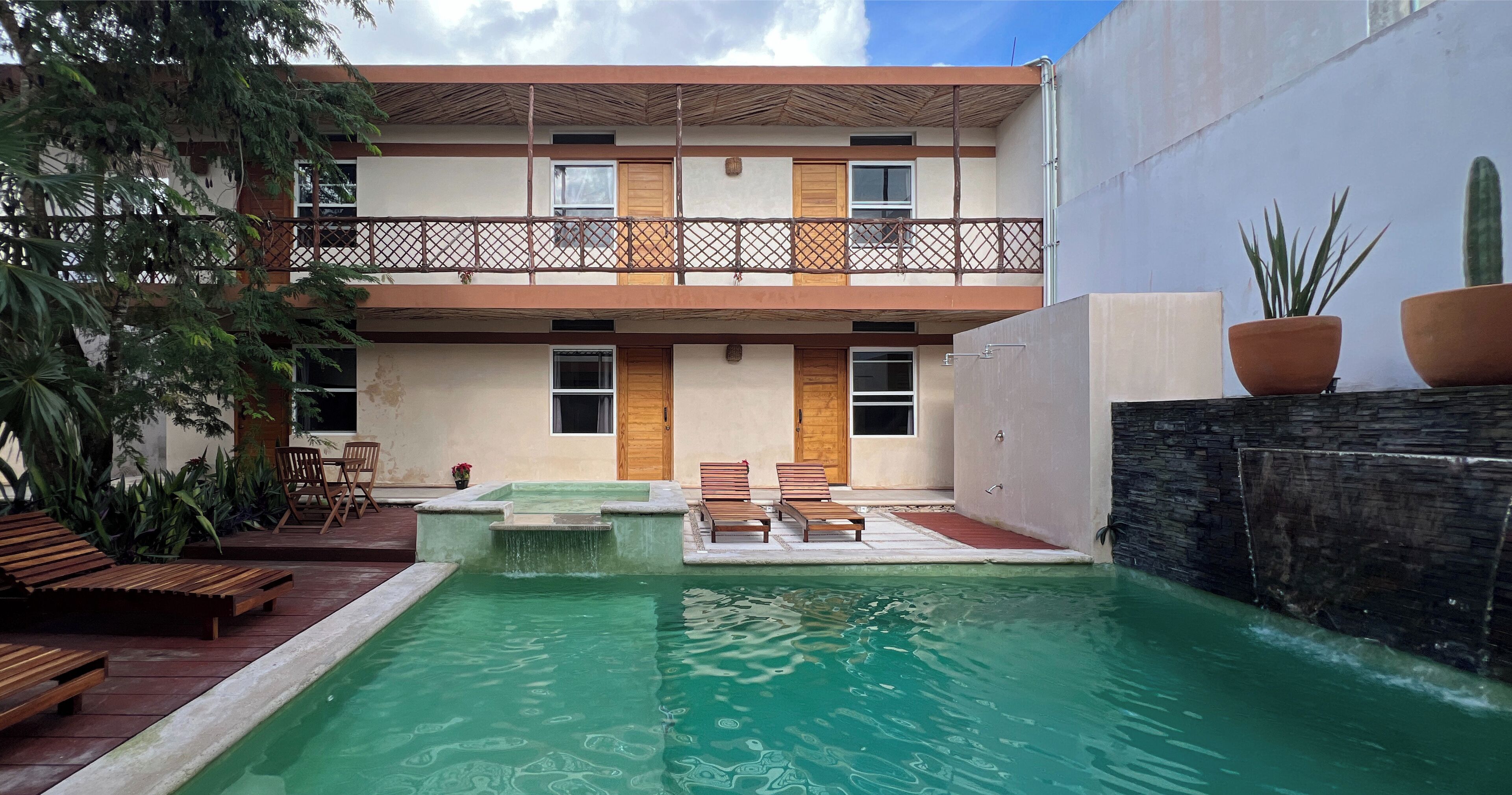 A two-story building with a pool, wooden deck, and outdoor seating area.